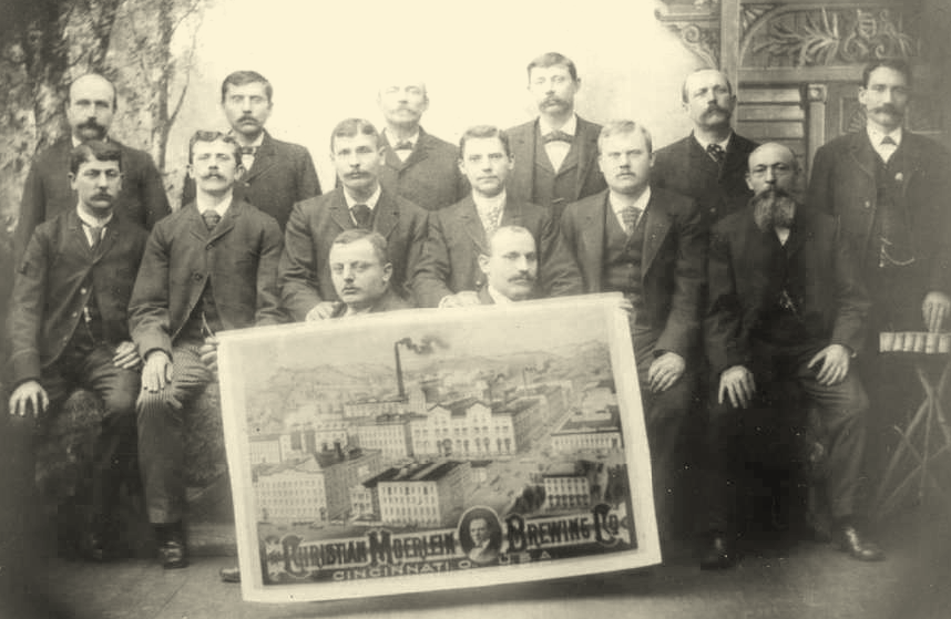 Christian Moerlein historical image. Founders from the 1800s standing around a large photo of the original brewery.